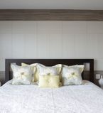 Chambre à coucher présentant un mur recouvert de moulures à feuillure brunes encadrant des moulures à feuillure blanches